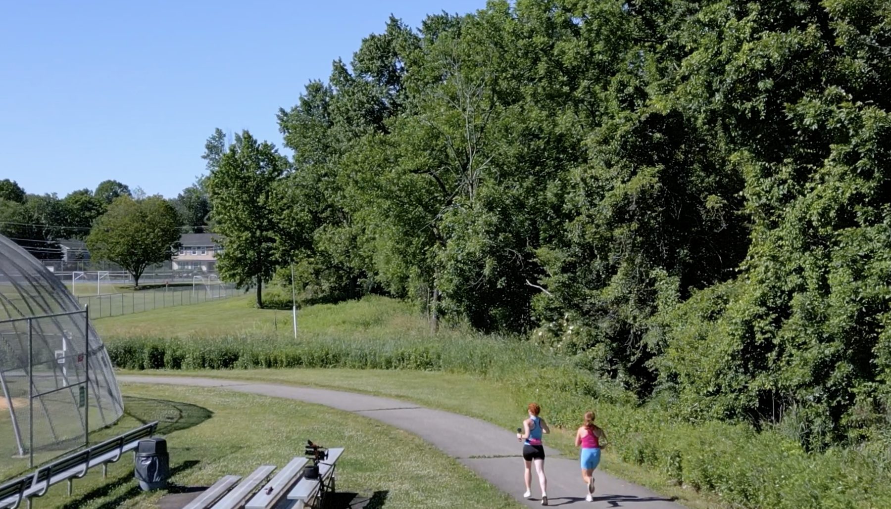 Two runners on a wooded path at first light, from The Miles We Carry.